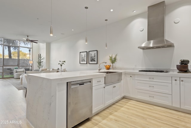 kitchen featuring sink, extractor fan, white cabinetry, hanging light fixtures, and stainless steel dishwasher