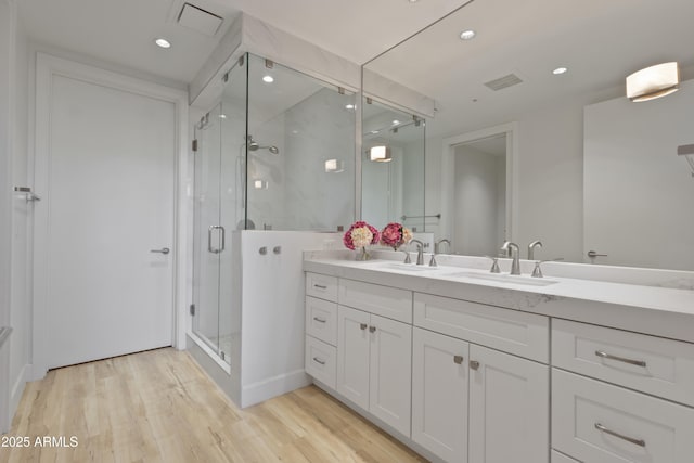 bathroom with hardwood / wood-style flooring, vanity, and an enclosed shower