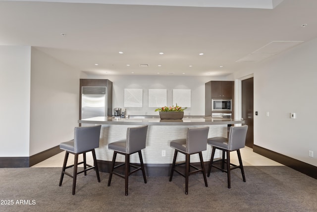 kitchen featuring dark brown cabinets, built in appliances, a kitchen breakfast bar, and a large island