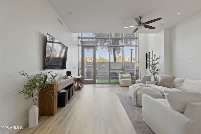 living room featuring expansive windows, ceiling fan, and light hardwood / wood-style flooring