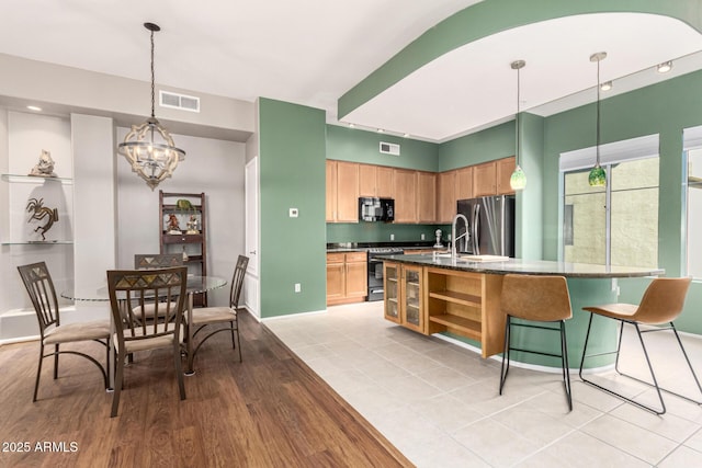 kitchen with sink, stainless steel appliances, light tile patterned flooring, decorative light fixtures, and a chandelier