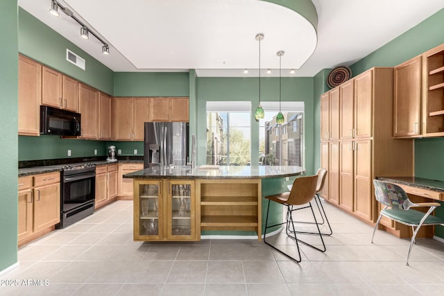 kitchen featuring a kitchen island, dark stone countertops, a kitchen bar, hanging light fixtures, and black appliances