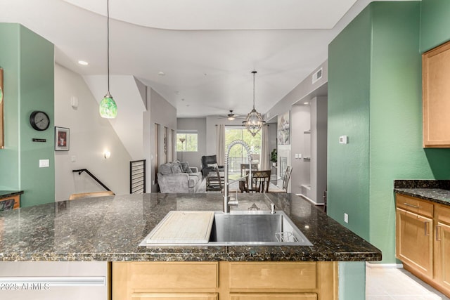 kitchen featuring decorative light fixtures, sink, and dark stone countertops