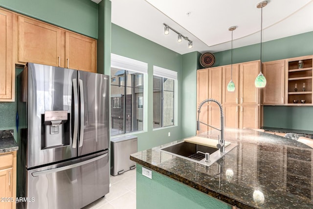 kitchen featuring light tile patterned floors, sink, stainless steel fridge with ice dispenser, decorative light fixtures, and dark stone counters