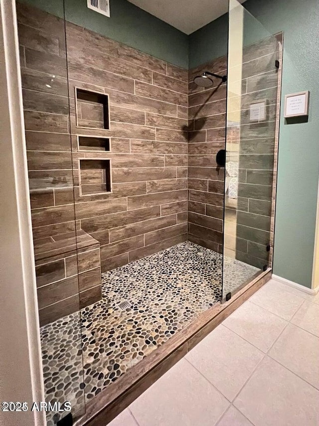 bathroom featuring tile patterned flooring and a tile shower