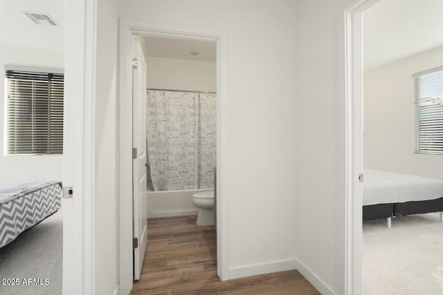 ensuite bathroom with shower / bathtub combination with curtain, visible vents, wood finished floors, and ensuite bathroom