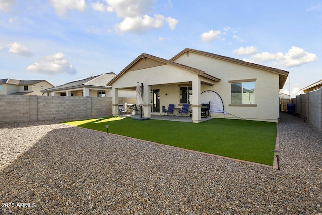 back of house featuring stucco siding, a fenced backyard, a lawn, and a patio