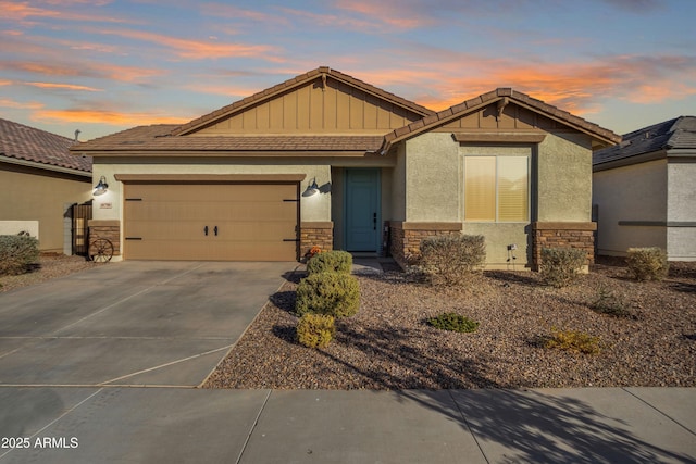 craftsman-style home featuring a garage, driveway, stone siding, a tile roof, and stucco siding