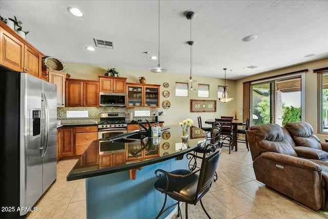 kitchen featuring visible vents, appliances with stainless steel finishes, a kitchen breakfast bar, and light tile patterned floors
