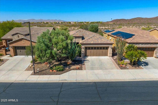view of front of house featuring concrete driveway, stucco siding, a mountain view, an attached garage, and a tile roof