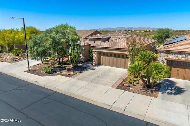 view of front of house featuring a mountain view, a garage, concrete driveway, and a tile roof
