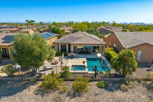 rear view of house with a fenced in pool, a patio area, outdoor dining area, a fenced backyard, and a tiled roof