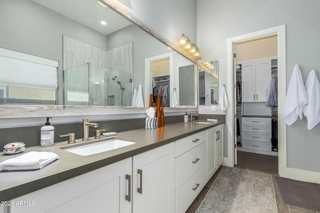 full bathroom with a stall shower, a sink, a spacious closet, and double vanity