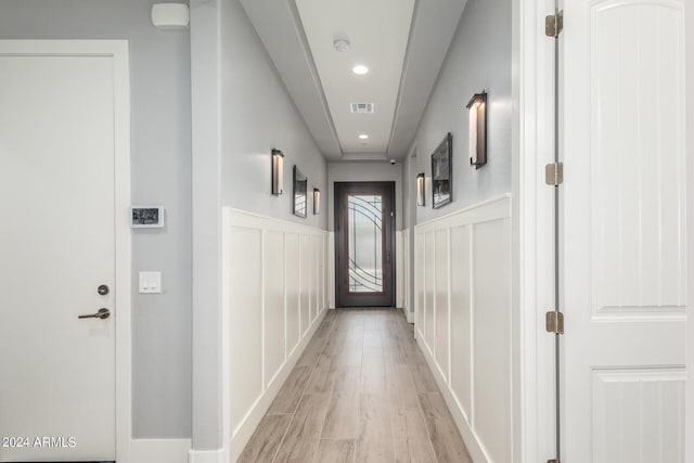 hallway with visible vents, wainscoting, light wood-style floors, a decorative wall, and recessed lighting