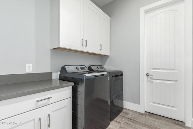 laundry area featuring light wood-style flooring, washing machine and clothes dryer, cabinet space, and baseboards