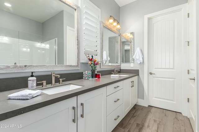 bathroom with double vanity, a sink, and wood finished floors