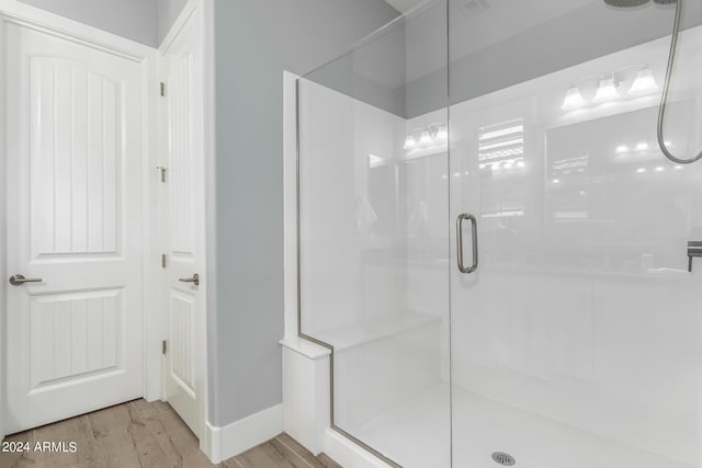 bathroom with wood finished floors and a shower stall