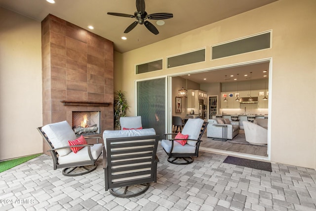 view of patio / terrace with an outdoor living space with a fireplace and a ceiling fan