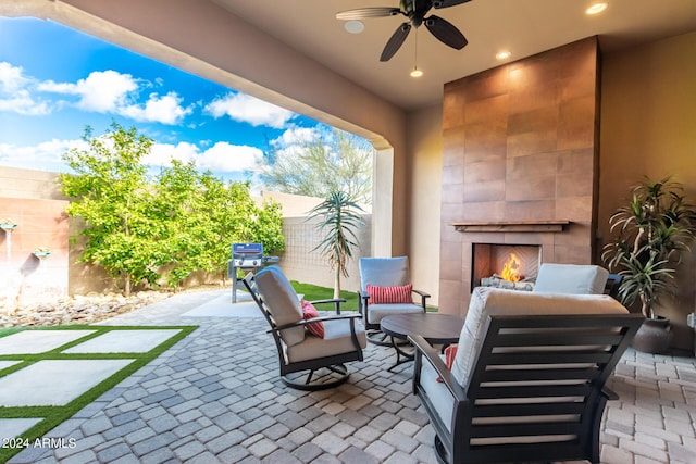 view of patio / terrace with an outdoor living space with a fireplace, fence, and a ceiling fan