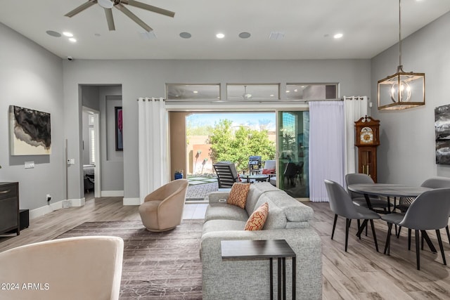 living area featuring recessed lighting, ceiling fan with notable chandelier, visible vents, baseboards, and light wood finished floors