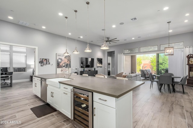 kitchen featuring beverage cooler, visible vents, dark countertops, an island with sink, and a sink