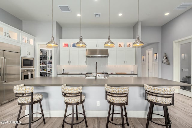 kitchen with light wood-type flooring, visible vents, under cabinet range hood, and built in appliances