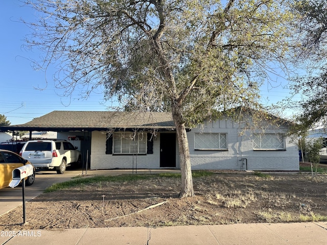 ranch-style home with an attached carport, brick siding, and driveway