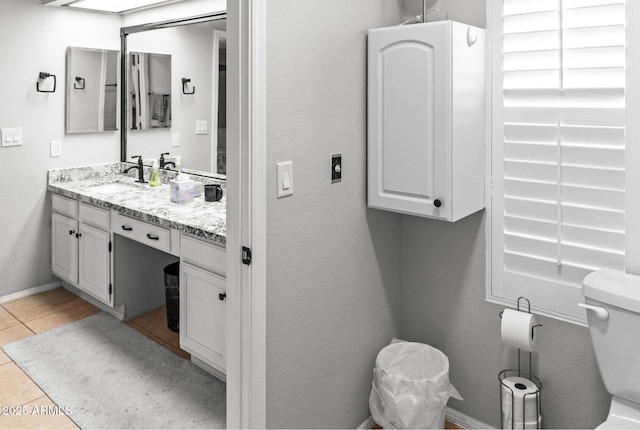bathroom with toilet, tile patterned floors, baseboards, and vanity