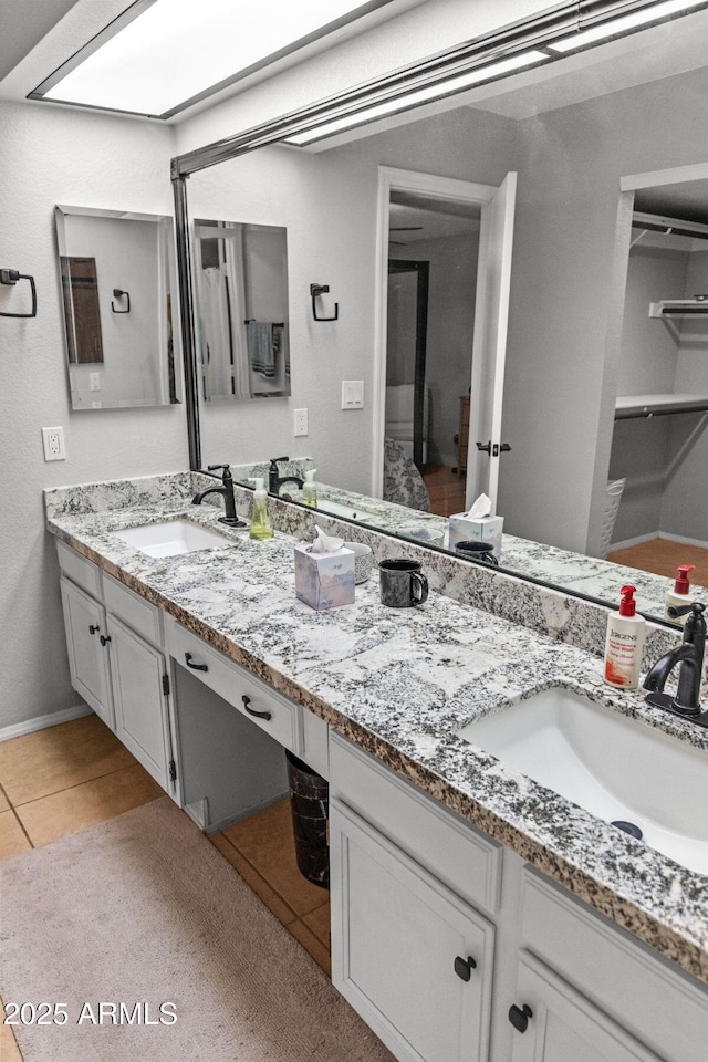 full bathroom with double vanity, a sink, baseboards, and tile patterned flooring