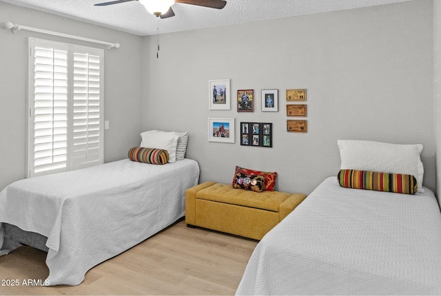bedroom featuring light wood-type flooring, a textured ceiling, and ceiling fan