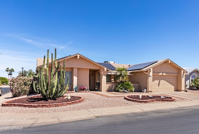 ranch-style house featuring an attached garage, driveway, roof mounted solar panels, and stucco siding