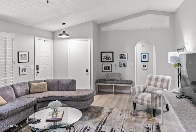 living area with arched walkways and light wood-style flooring