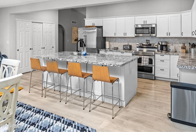 kitchen featuring light wood-type flooring, white cabinets, visible vents, and stainless steel appliances