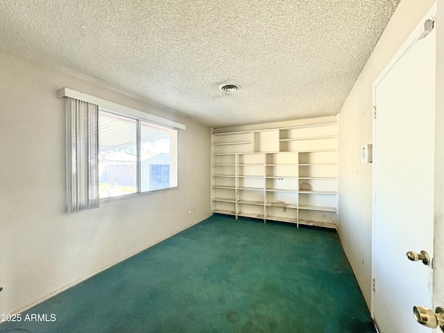 unfurnished room featuring visible vents, a textured ceiling, and dark colored carpet