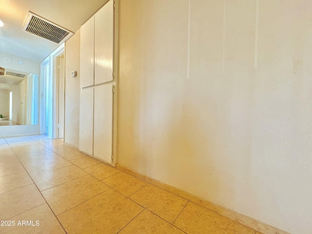 hall featuring light tile patterned flooring and visible vents