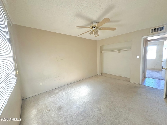 unfurnished bedroom featuring a closet, visible vents, a textured ceiling, and a ceiling fan