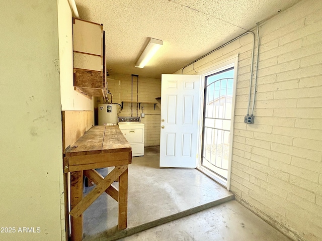 interior space with gas water heater, brick wall, washer / clothes dryer, and unfinished concrete flooring