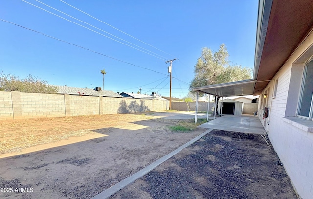 view of yard featuring a patio area, an outbuilding, a fenced backyard, and a shed