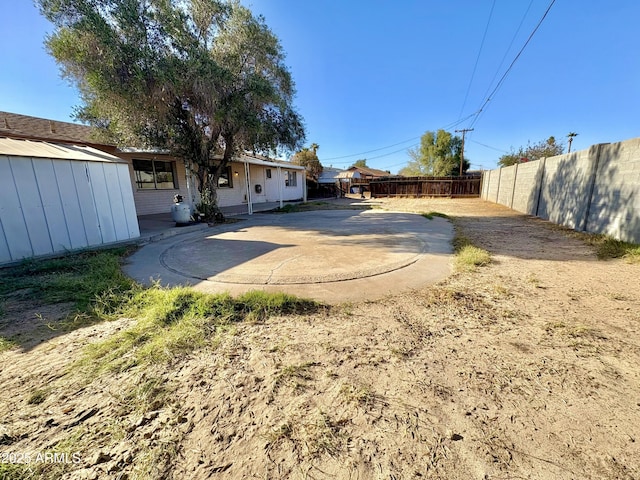 view of yard featuring a patio, an outdoor structure, and fence