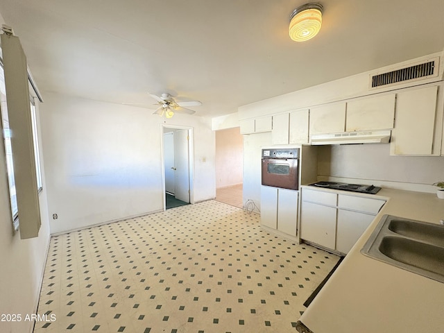 kitchen featuring visible vents, under cabinet range hood, a sink, wall oven, and black electric cooktop