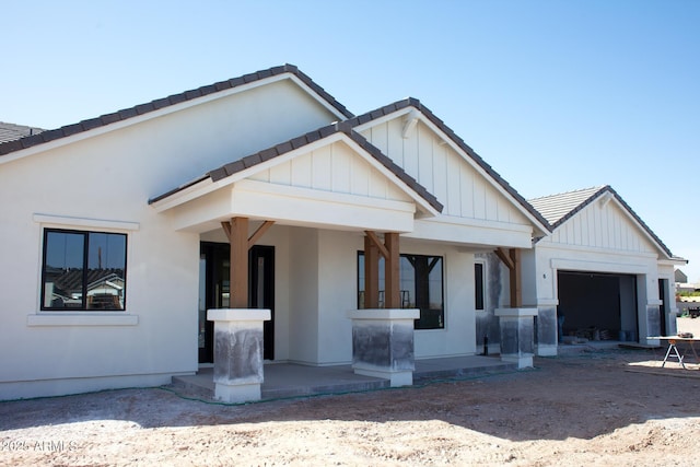 modern inspired farmhouse featuring board and batten siding, a tile roof, and a garage