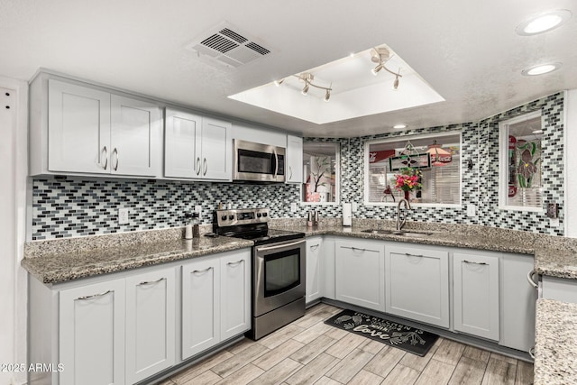 4013 E Delta Cir, Mesa, AZ 85206 - kitchen featuring appliances with stainless steel finishes, a raised ceiling, backsplash, light wood-type flooring, and light stone countertops