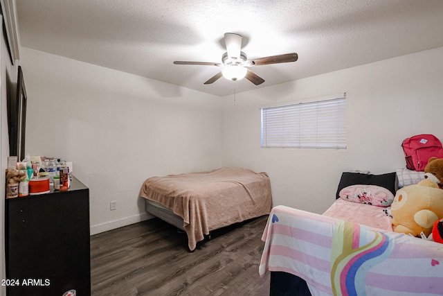 bedroom featuring dark wood-type flooring, ceiling fan, and a textured ceiling