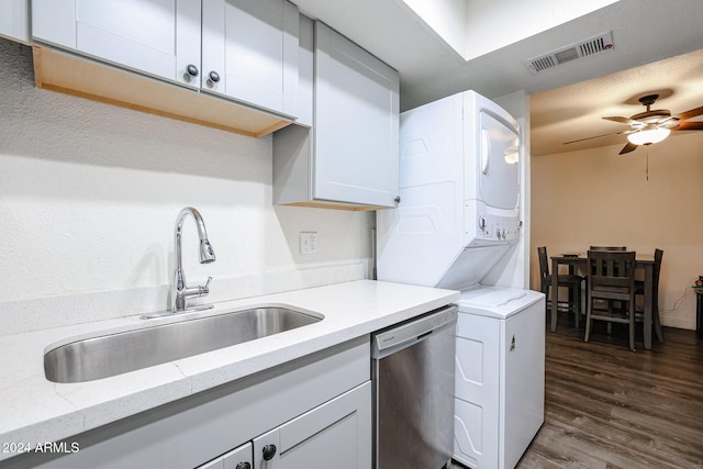 kitchen featuring stainless steel dishwasher, visible vents, a sink, dark wood-type flooring, and stacked washer / drying machine