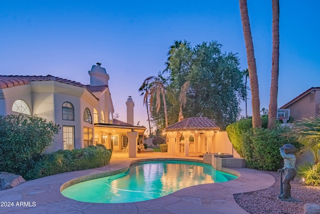 pool at dusk featuring a patio