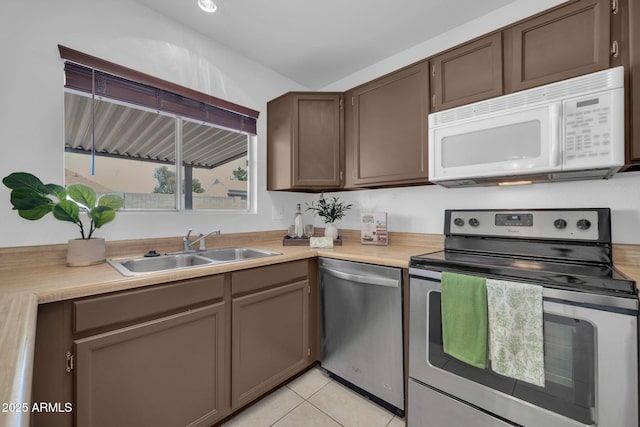 kitchen with light countertops, a sink, light tile patterned floors, and stainless steel appliances