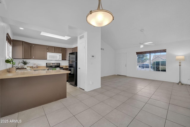 kitchen featuring vaulted ceiling, light countertops, white microwave, freestanding refrigerator, and stainless steel electric stove