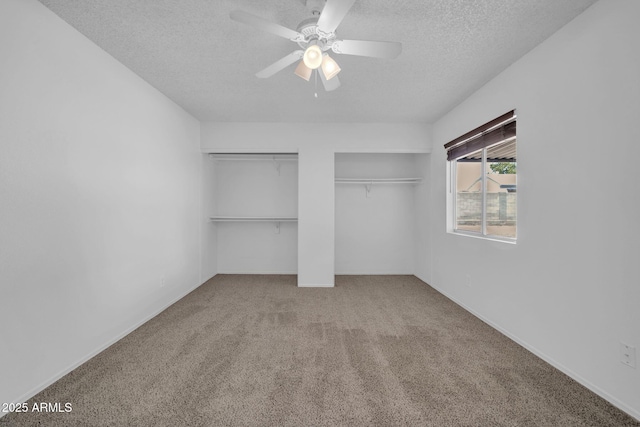 unfurnished bedroom featuring a ceiling fan, a textured ceiling, multiple closets, and carpet