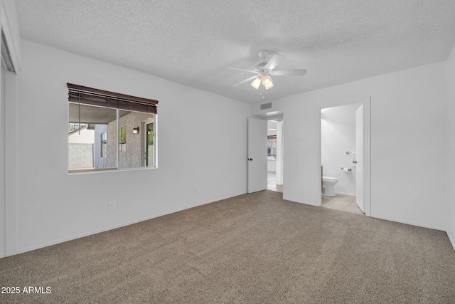 unfurnished bedroom featuring visible vents, ensuite bathroom, baseboards, a textured ceiling, and carpet flooring