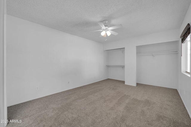 unfurnished bedroom with multiple closets, a ceiling fan, a textured ceiling, and carpet floors